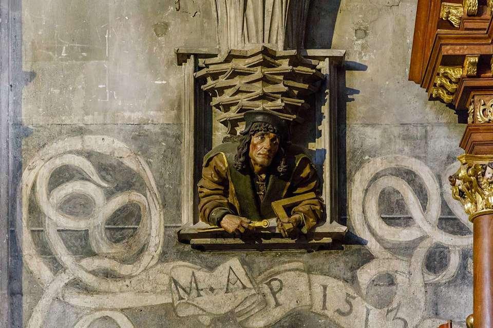 Piccolo volto scolpito che si affaccia da una finestra sotto il pulpito dello Stephansdom